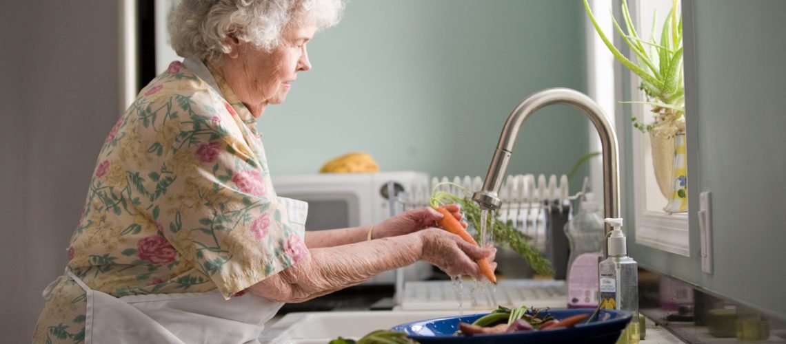 Elderly parents at home living with their children and washing a carrot